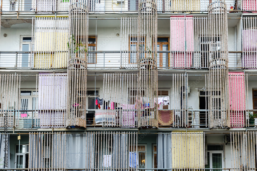 Facade of an apartment house, decorated with bamboo trunks, affordable low-cost housing, drying clothes hanging on a clothesline.