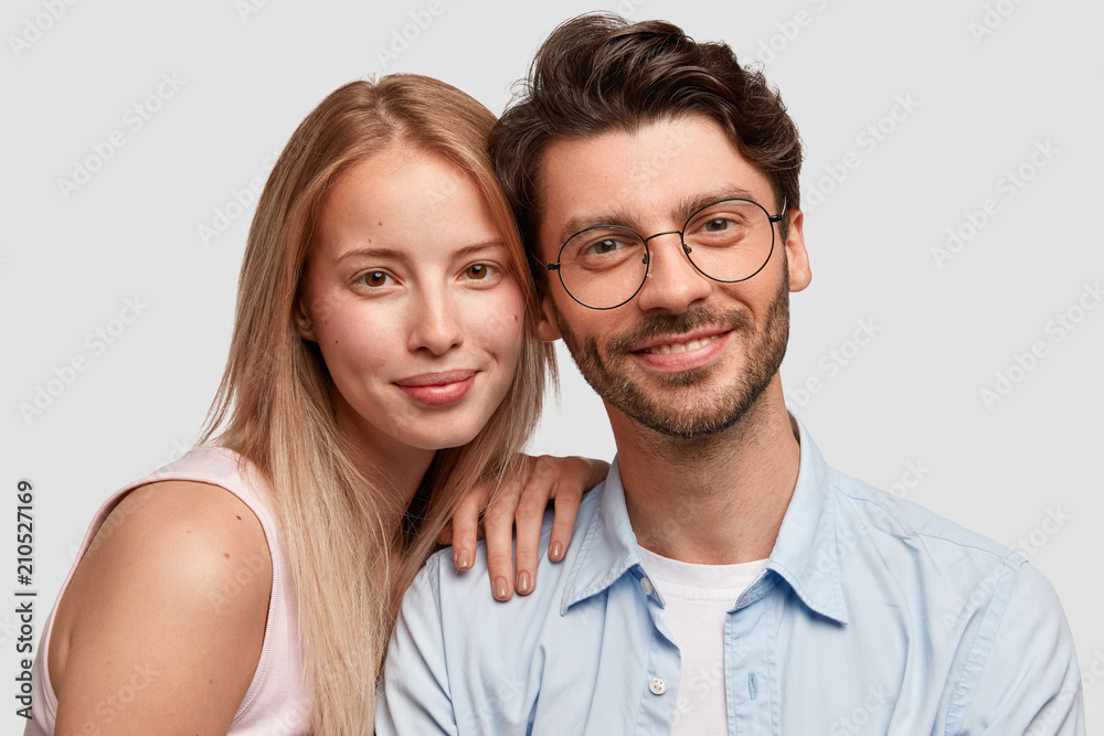 People and closeness concept. Portrait of happy couple in love, stand close to each other, look positively at camera, enjoy togetherness and leisure time, isolated on white studio background. People and closeness concept. Portrait of happy couple in love, stand close to each other, look positively at camera, enjoy togetherness and leisure time, isolated on white studio background.