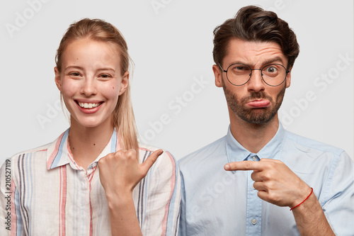 Картината върху платно Positive young glad European female with blonde hair indicates with thumb at her