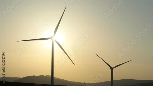 wind turbines blades rotation in motion in beautiful summer day with bright sunlight and mountain area on background clear sky nobody outside converting wind energy electrical engineering equipment photo