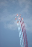 Formacja szybkich samolotów, w biało-czerwonych barwach, leci bardzo blisko siebie, puszczając dym z każdego samolotu, dym biały i czerwony