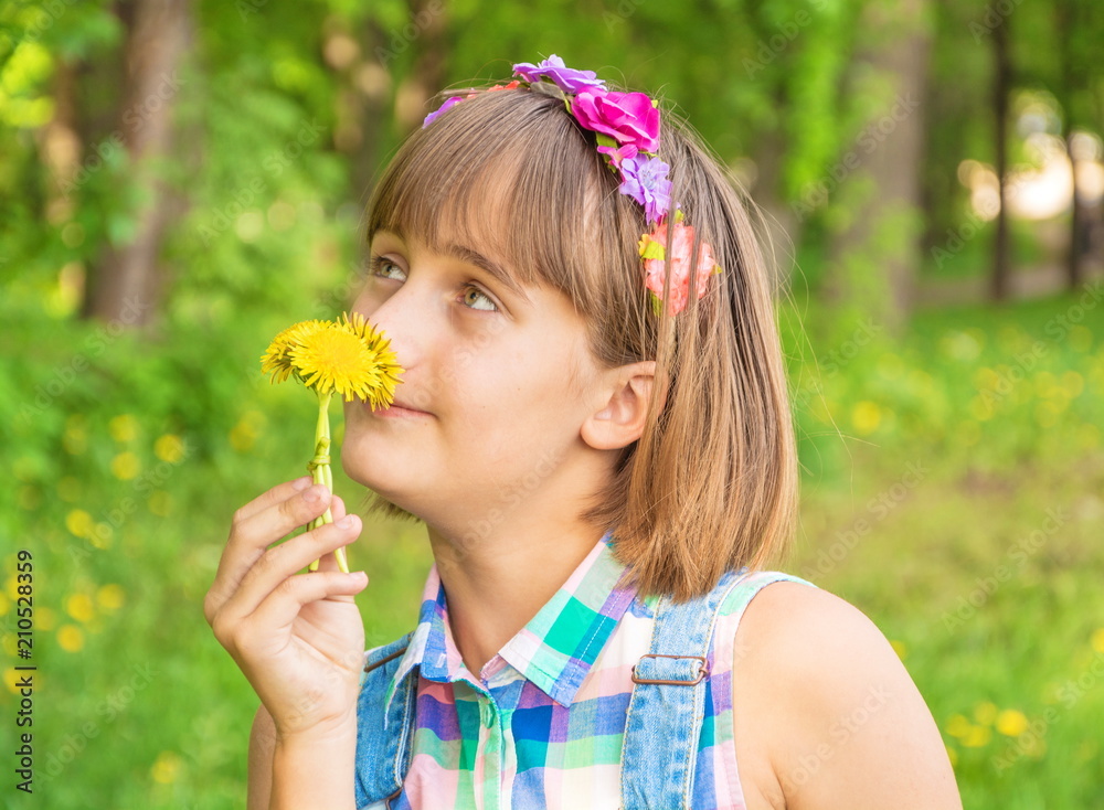 Portrait of a cute teenage girl with a wreath on her head and dandelions in her hands