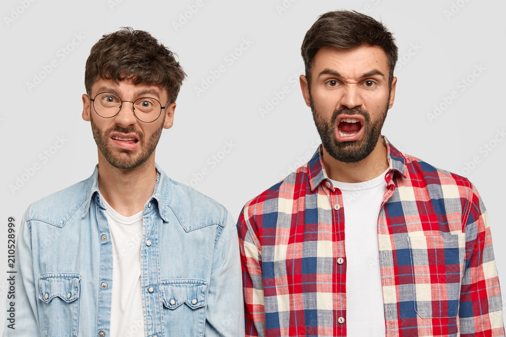 Tired displeased male groupmates being fed up with cramming and preparation for exam, frown face in displeasure, wants to go on disco, have friendly relationship. Two fellows express negative emotions Tired displeased male groupmates being fed up with cramming and preparation for exam, frown face in displeasure, wants to go on disco, have friendly relationship. Two fellows express negative emotions