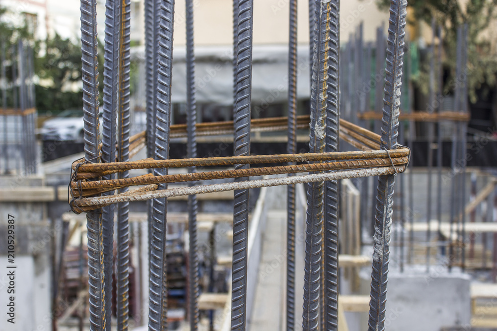 Front close-up shot of new textured iron sticks in concrete column at construction site