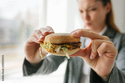 A young girl shows that she does not like a burger. Conceptual image of refusal from unhealthy eating.