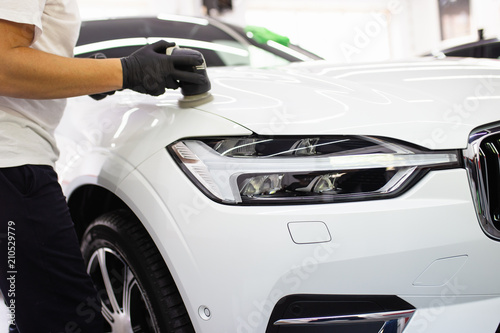 Car detailing - Worker with orbital polisher in auto repair shop. Selective focus.