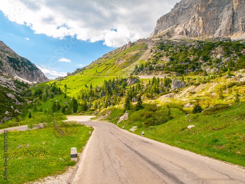 Asphalt road, green meadows and dolomite rocks at Passo Falzarego, Dolomites, Italy. photo