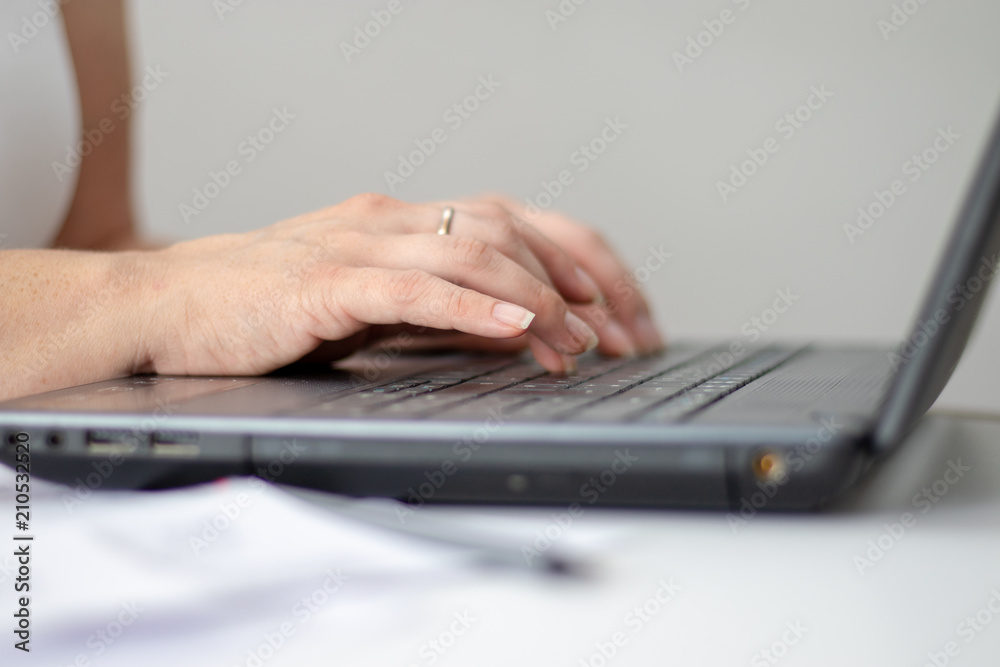 Woman typing with both hands on her black notebock in the office