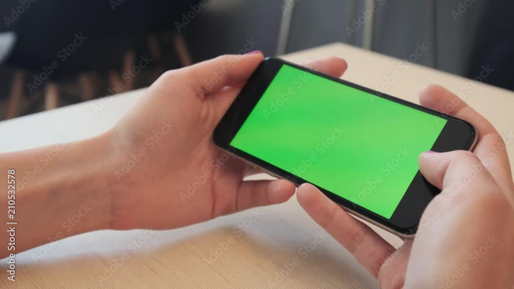 Beautiful girl holding a smartphone in the hands of a green screen green screen, hand of man holding mobile smart phone with chroma key green screen on white background, new technology concept. Beautiful girl holding a smartphone in the hands of a green screen green screen, hand of man holding mobile smart phone with chroma key green screen on white background, new technology concept.