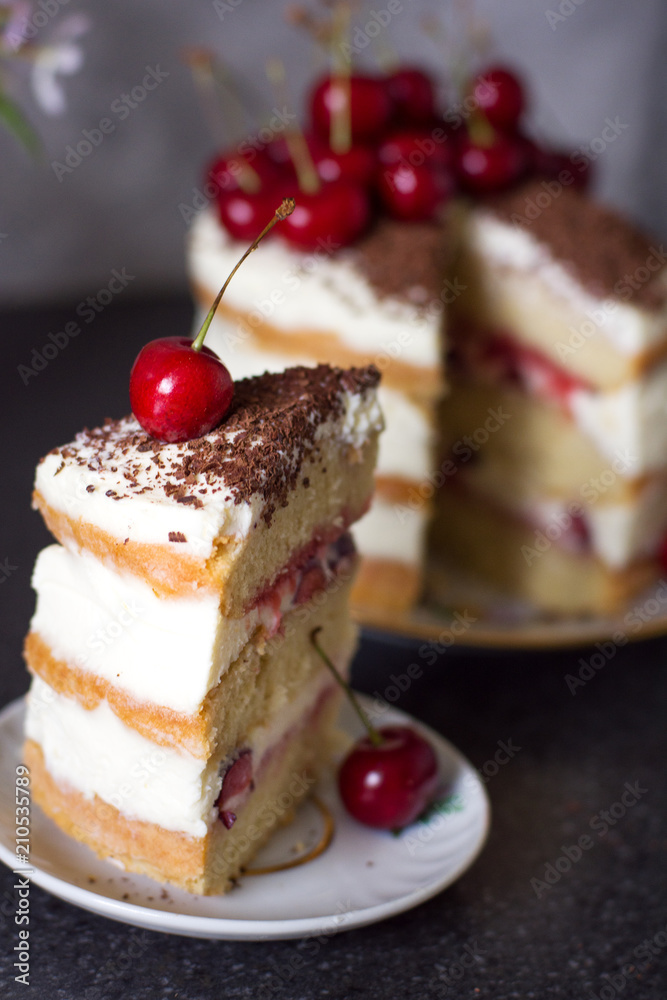 Biscuit vanilla cake with cream and cherry with chocolate. Celebration. A delicious homemade cake. Soft focus.