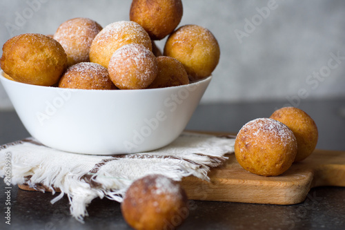 Donuts close-up. Italian fritters -Castagnole  traditional dish on a gray background in a white bowl on a wooden board.