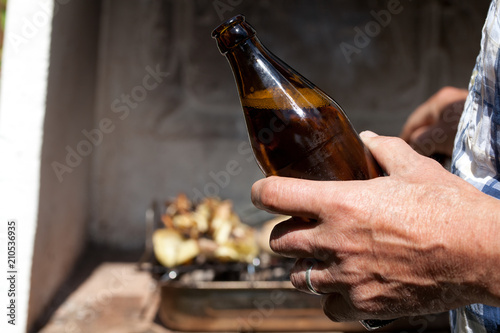 bottle of beer in man's hands while making barbecue