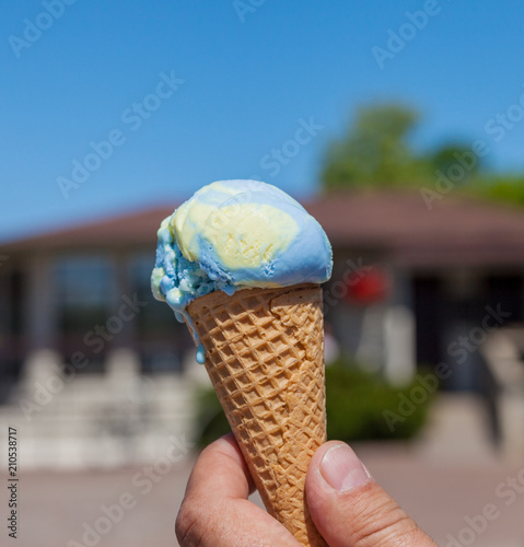 Male hand holding ice cream cone.