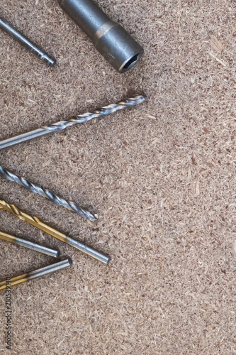 Background with copy space on the hobby, DIY, hand tools, house repairing theme. Metallic screws, drills and screwdriver socket laying on the flake board.