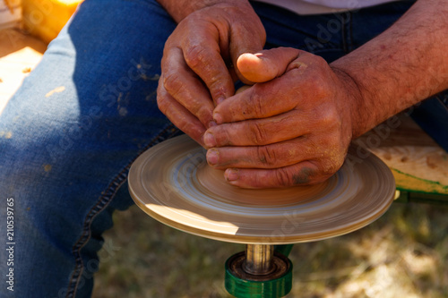 Hands of mature man making pottery on pottery wheel. Close-up