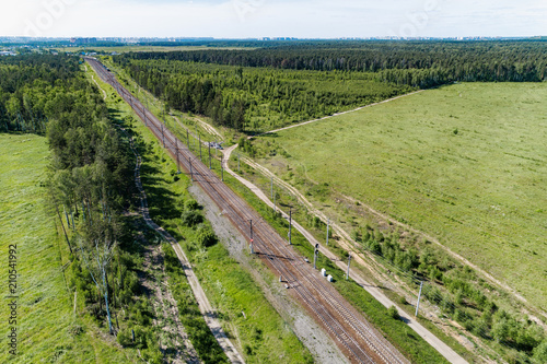 A railway track passing through the forest and field.