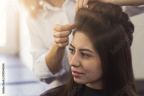 Hairstylist make curls on brown client's hair