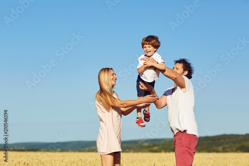 A happy family is enjoying fun with a child outdoors in a summer field.