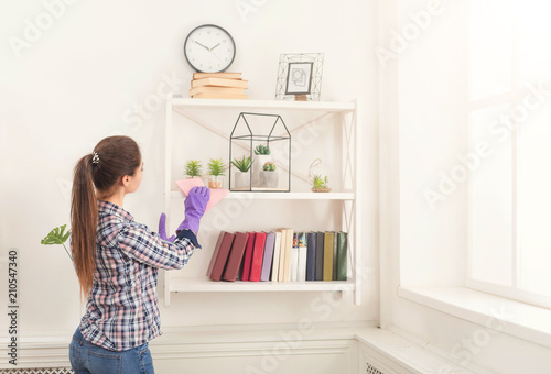 Woman cleaning dust from bookshelf