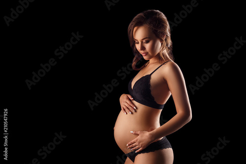 pregnant woman in underwear on black background concept of motherhood © Екатерина Переславце