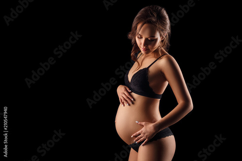 pregnant woman in underwear on black background concept of motherhood