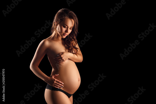 pregnant woman in lingerie on black background © Екатерина Переславце