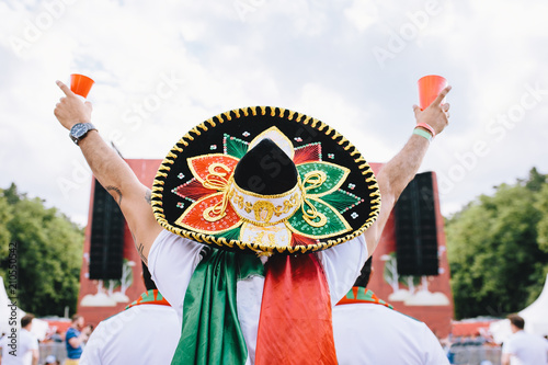 Mexican fans in uniform and sombrero are happy for their team during the World Cup