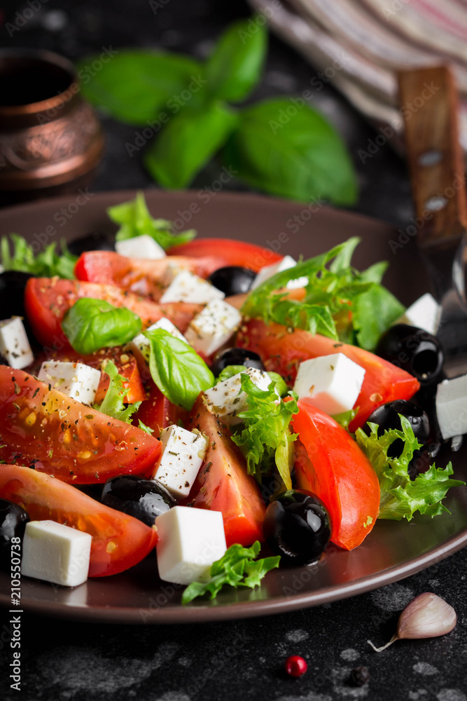Salad with tomatoes, feta, olives and Basil, serving on a dark background