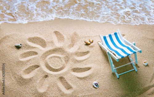 Fototapeta Naklejka Na Ścianę i Meble -  Deckchair on a beach with a sun drawn on the sand