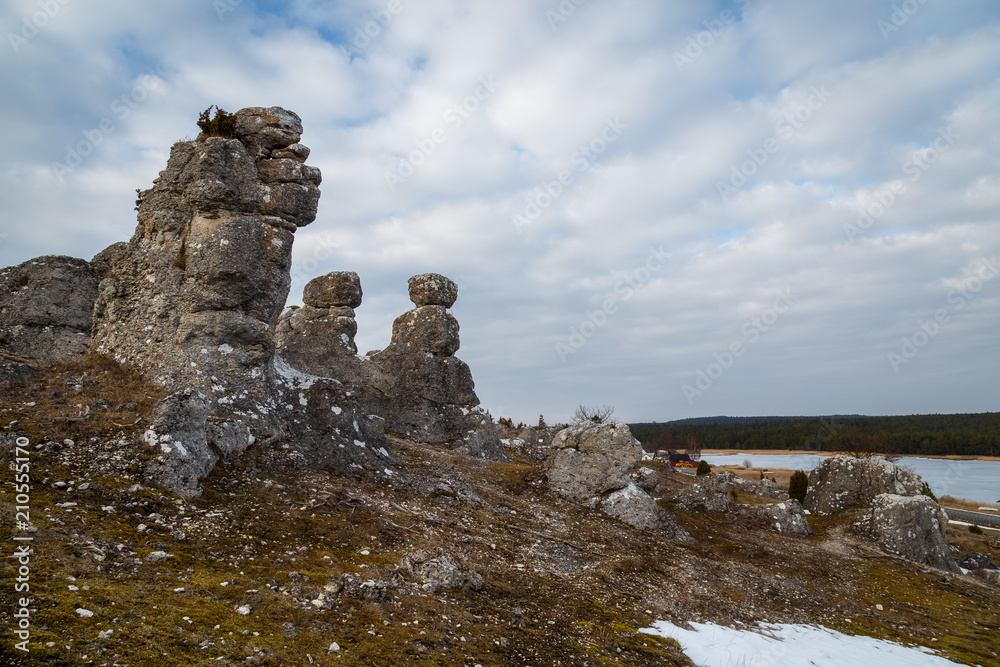 Standing rocks on a hill side with a lake and forest in the background Standing rocks on a hill side with a lake and forest in the background