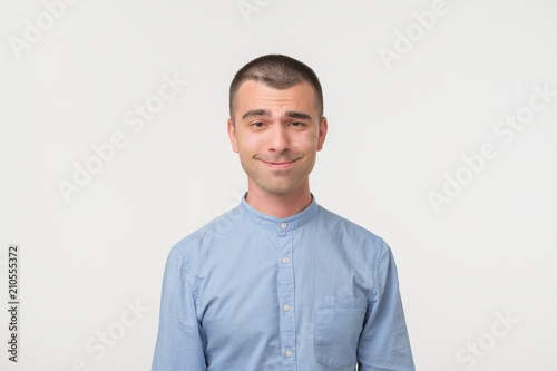 Handsome latino man shows surprised smile grimace or facial expression, isolated on white background.