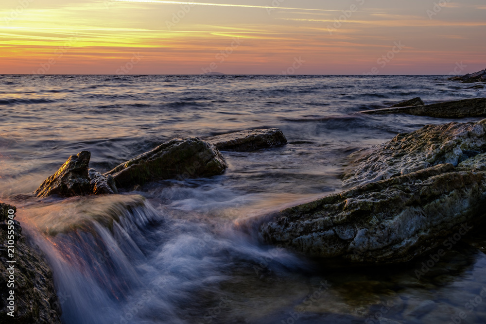 waves flowing over stones at sunset