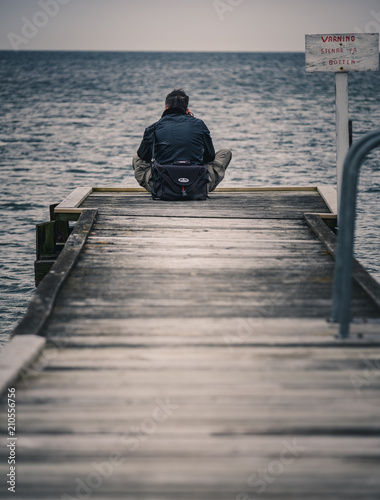 man sitting on a wooden jetty