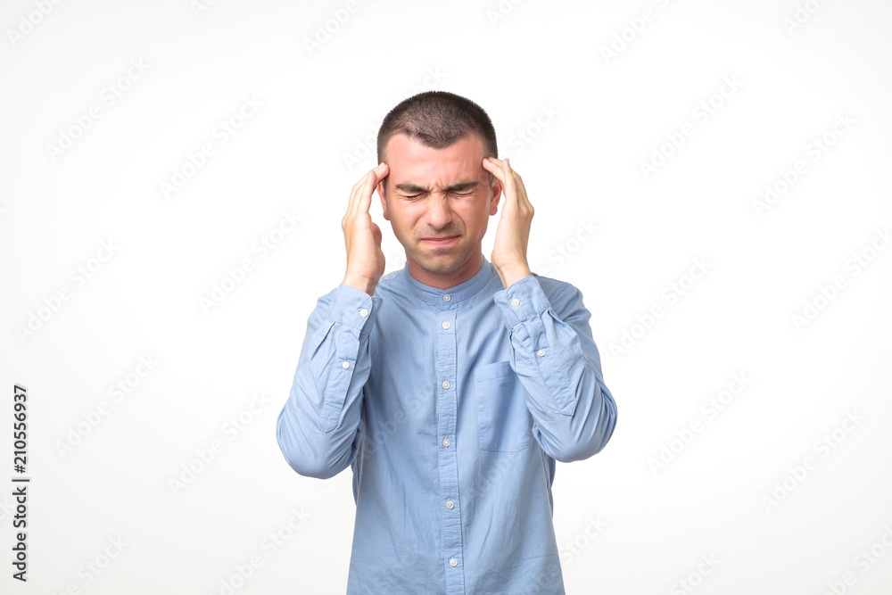 Portrait of young man having a headache while standing over white background. Portrait of young man having a headache while standing over white background.