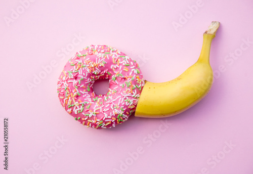 Fresh sweet donut and banana on pink background. Abive view photo