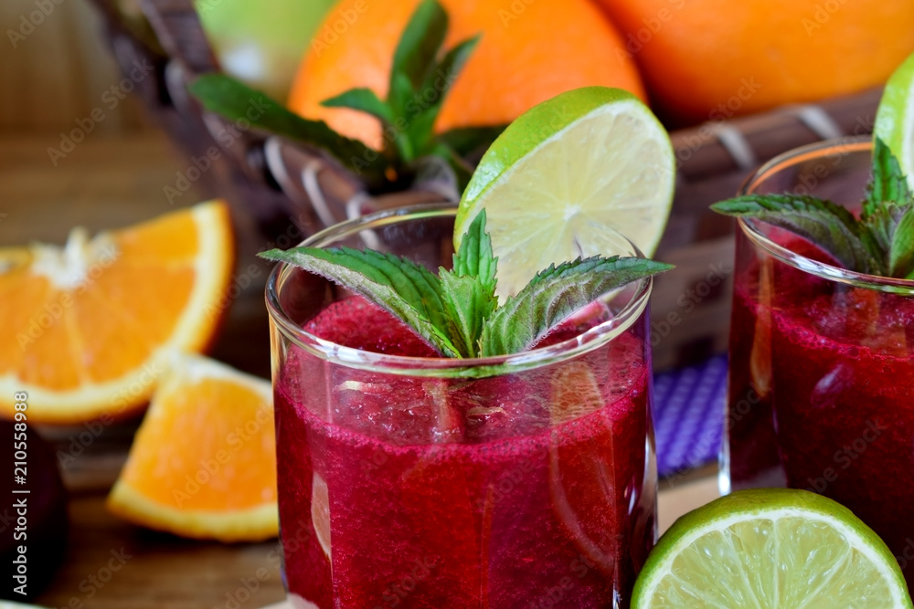 Fototapeta premium Smoothie with beet and orange in a glass decorated with mint and a slice of lime