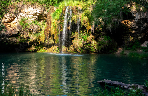 Waterfall and a beautiful lagoon lake for relaxing in the summer forest.