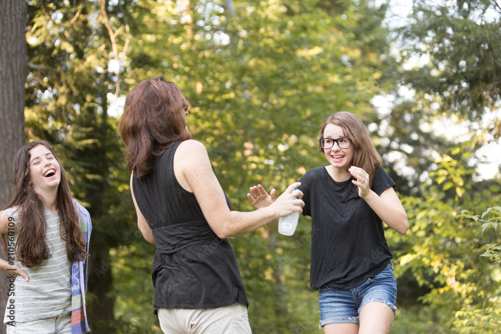 Mother trying to spray teenage daughter with bug spray Mother trying to spray teenage daughter with bug spray