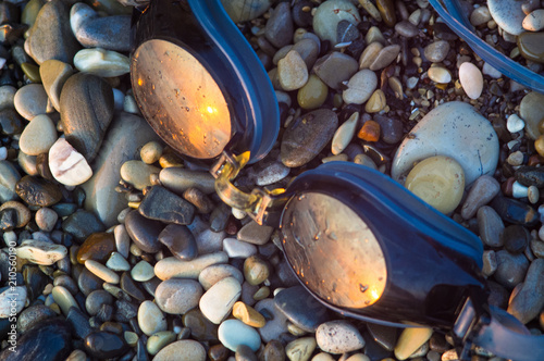 eyeglasses for swimming on a pebble beach in the sea waves