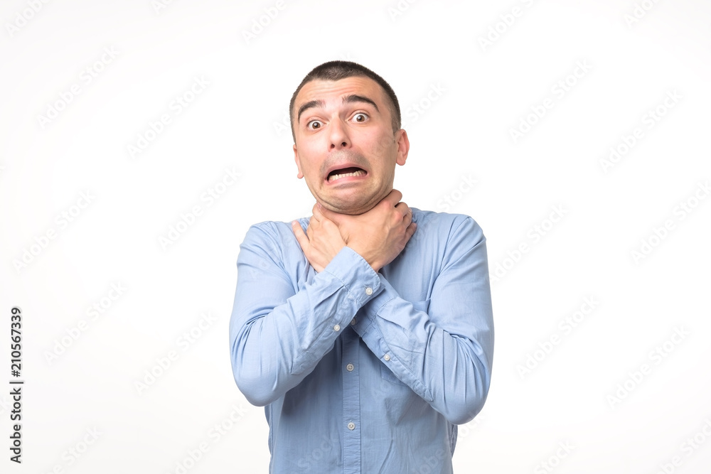 Young spanish man in blue shirt having asthma attack or choking suffering from respiration problem.