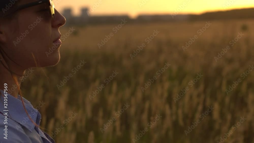 Unity With Nature Concept. Close-up - Unidentified Young Woman In Casual Clothes And With A Backpack Meditating on The Field On A Sunny Summer Day Unity With Nature Concept. Close-up - Unidentified Young Woman In Casual Clothes And With A Backpack Meditating on The Field On A Sunny Summer Day