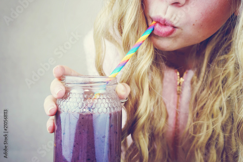 Preciosa chica joven y rubia bebiendo un smoothie de frutos rojos  photo