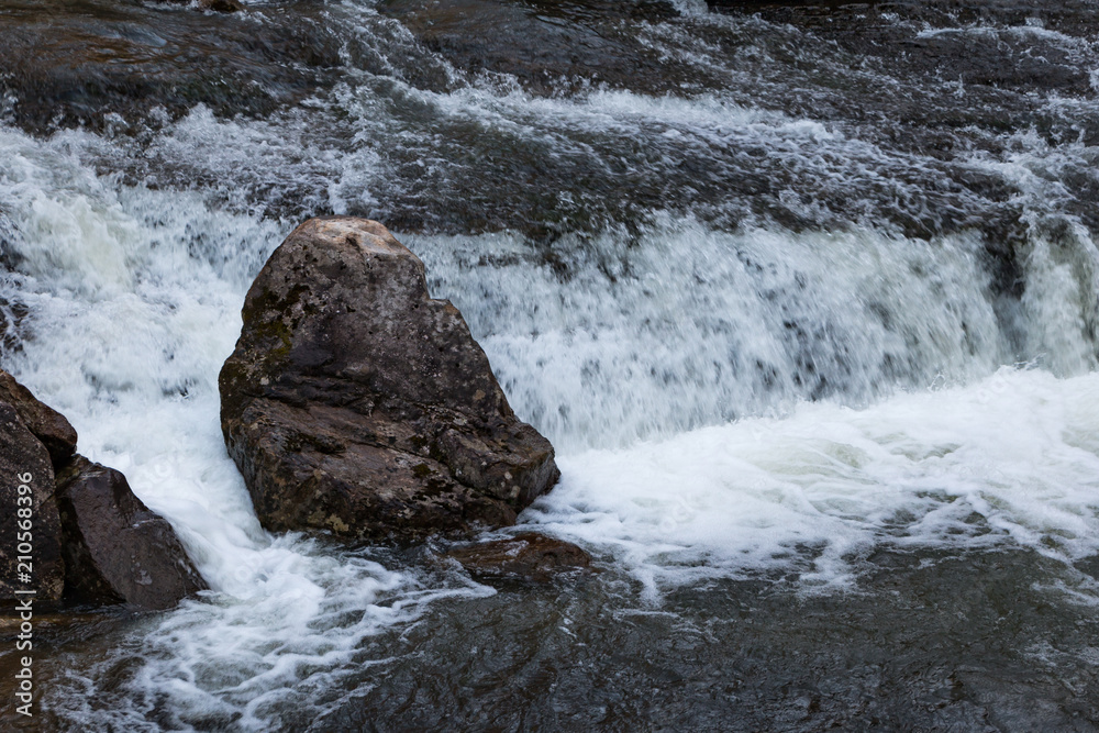 A little waterfall with a prominent stone in the foreground. A little waterfall with a prominent stone in the foreground.