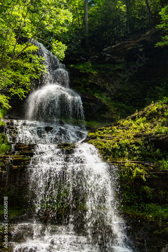 A Waterfall in a forest in Southern West Virginia  cascading down lush green moss covered rocks.
