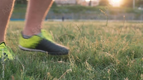 Slow motion football stunts. The football player throws the ball alternately with his feet. A teenager is playing on an abandoned football field at sunset on a sunny day in the summer. Football field