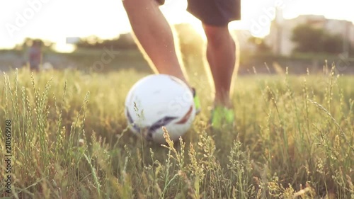 Slide slow motion a defocusing in focus on the football player's figures giving a pass ball. A teenager is playing on an abandoned football field at sunset on a sunny day in the summer. Football field