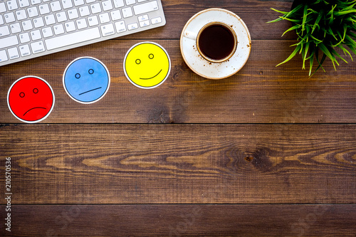 Customer satisfaction concept. Emoji smile, neutral, sad on work desk on dark wooden background top view copy space