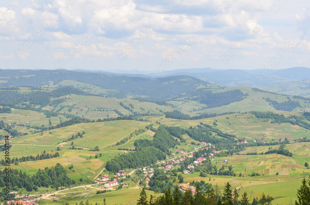 Outstanding landscape from a height. Green forest and village in the mountains against the sky. Ukrainian Carpathians