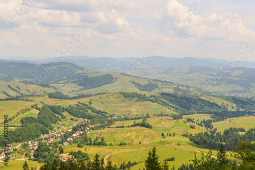 Fototapeta Naklejka Na Ścianę i Meble -  Outstanding landscape from a height. Green forest and village in the mountains against the sky. Ukrainian Carpathians