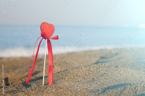 Valentine's day greeting card concept, red heart on pristine sandy beach, honeymoon vacation background. photo